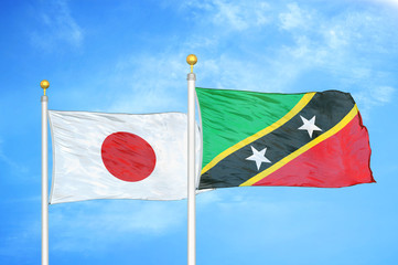 Japan and Saint Kitts and Nevis two flags on flagpoles and blue cloudy sky