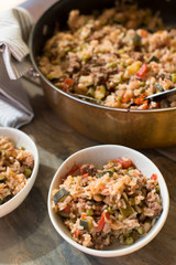 A casserole with rice and tomatoes and beans made in a copper pot and served in white dishes for a healthy meal