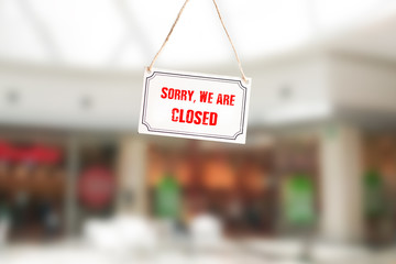 A closed sign hanging in the glass doorway of a shop