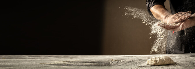 Photo of flour and men hands with flour splash. Cooking bread. Kneading the Dough. Isolated on dark background. Empty space for text