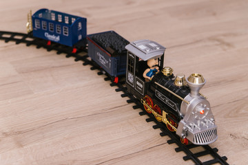 Children's railway. Steam train with cars for the game. There are children's toys on the floor.