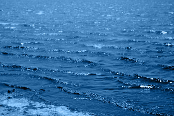 Defocused water background with bokeh  lights. Abstract blurry backdrop of waves.