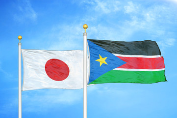 Japan and South Sudan two flags on flagpoles and blue cloudy sky