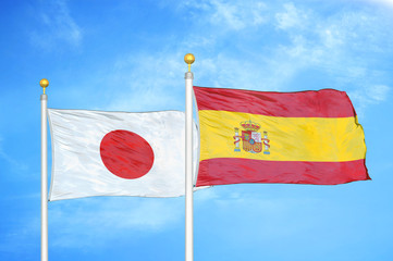 Japan and Spain two flags on flagpoles and blue cloudy sky