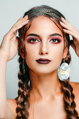 Portrait of a beautiful girl with dark lips and bright eye makeup with braids holding hands on her face. Girl of the month - October.
