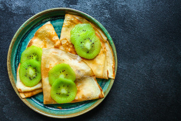  pancakes or thin crepes fritter with kiwi, sweet dessert Menu concept. food background. top view copy space for text