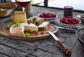 Assortment of cheese on a wooden tray with wine, on the table, house terrace, by day, there are no people