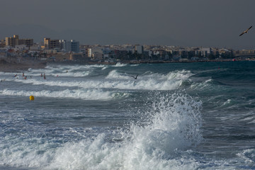 People bathing in a stormy Mediterranean Sea on a windy summer afternoon with the Andalusian town...