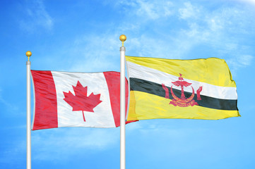 Canada and Brunei two flags on flagpoles and blue cloudy sky