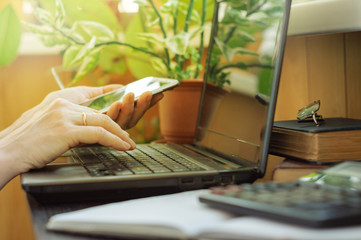 Home office concept. Woman working on a laptop, holding a telephone in her hand