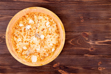 Pizza five cheeses on bamboo bottom, on wooden table, top view, space for text