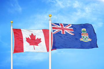 Fototapeta premium Canada and Cayman Islands two flags on flagpoles and blue cloudy sky