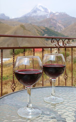 Two Glasses of Red Wine on a Glass Table with Mount Kazbek of Georgia in Background	