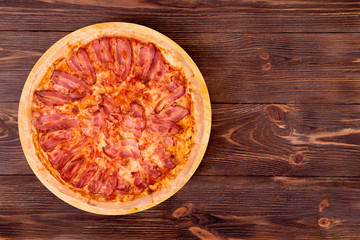 Pizza bacon on bamboo bottom, on wooden table, top view, space for text