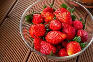 ripe strawberries in a glass dish on a wooden table