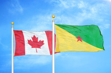 Canada and French Guiana two flags on flagpoles and blue cloudy sky