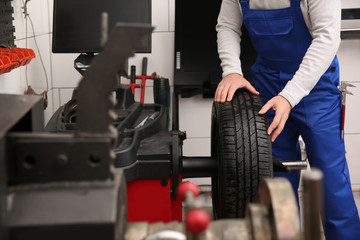 Naklejka na ściany i meble Mechanic working with wheel balancing machine at tire service, closeup