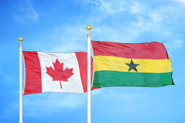 Canada and Ghana two flags on flagpoles and blue cloudy sky