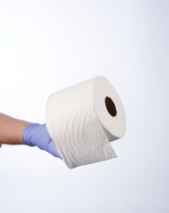 Left hand in blue glove holding a roll of toilet paper