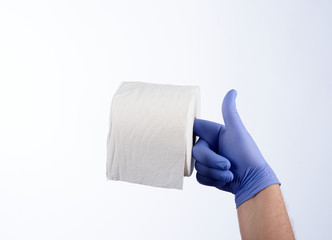 Right hand in blue glove holding with index finger a roll of toilet paper