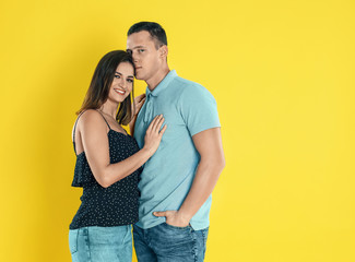 Naklejka premium Happy young couple hugging on yellow background. Space for text