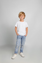 Cute little boy in casual outfit on light grey background