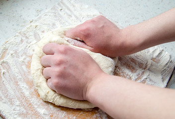 girl's hands knead the dough