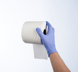 Right hand in blue glove holding a roll of toilet paper