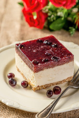 portion of red berry cake on plate on wood