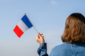 Woman hand with French swaying flag on the blue sky. France. Concept