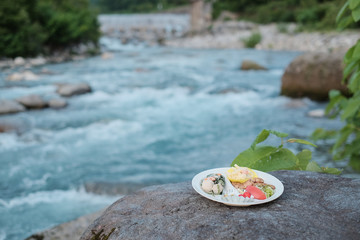 Fototapeta na wymiar 川辺の岩の上に置かれたワンプレートの食事