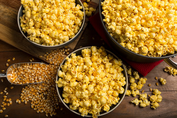 Fresh homemade Popcorn and kernels in bowls on wooden background overhead view. Great for movie night