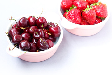 Ripe berries - strawberries and cherries in a plate. Still life with strawberries and cherries on grey background.