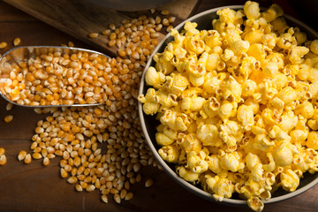 Fresh homemade Popcorn and kernels in bowls on wooden background overhead view. Great for movie night