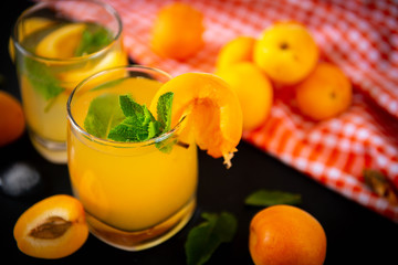 2 cups apricot lemonade with fresh apricots on a black , top view, juice