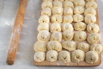 Russian dumplings stuffed with minced meat with onions on a wooden board.