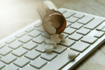 Different pills and computer keyboard on doctor's table.