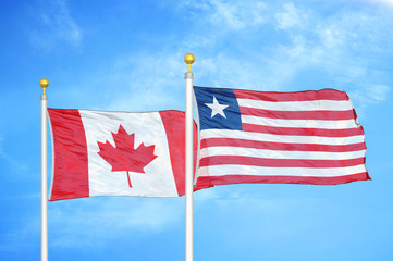 Canada and Liberia two flags on flagpoles and blue cloudy sky