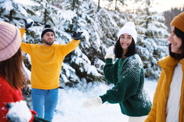 Happy friends playing snowballs outdoors. Winter vacation