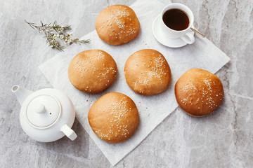 Group of freshly baked buns with sesame seeds. Buns for burgers. Tea with buns.