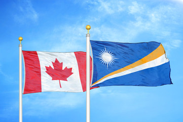 Canada and Marshall Islands two flags on flagpoles and blue cloudy sky