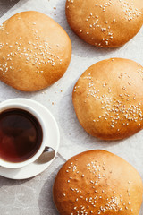 Group of freshly baked buns with sesame seeds. Buns for burgers. Tea with buns.