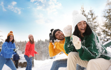 Group of friends playing snowballs outdoors. Winter vacation