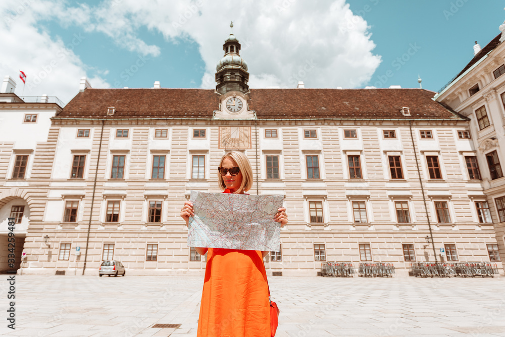 Wall mural woman tourist stands with a city map in vienna, austria