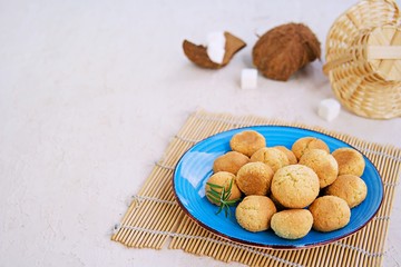 Ball-shaped sweet coconut cookies on a blue clay plate on a light concrete background. Coconut Baking