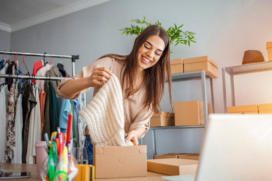 Women, owener of small business packing product in boxes, preparing it for delivery. Women packing package with her products that she selling online.