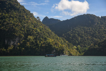 Fototapeta premium Island Hopping in Langkawi. Familly vacation and tours in Malaysia. Scenic views of small green rocky islands from the boat on Andaman Sea.