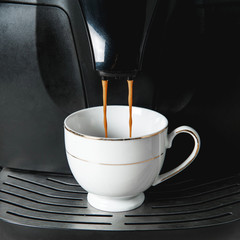 coffee is pouring into a white mug on a coffee machine