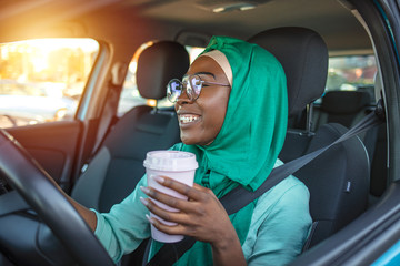 Smiling black muslim woman driving her vehicle. Beautiful Arab Muslim Woman wearing hijab in a car...