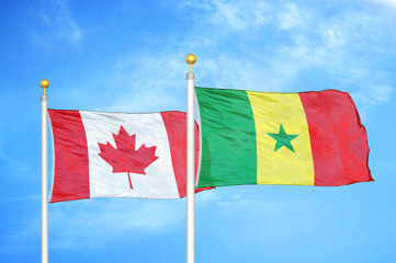 Canada and Senegal two flags on flagpoles and blue cloudy sky